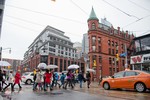 A walking tour passes the Flat Iron building at Church and Front Street, in the rain. Image by Herman Custodio